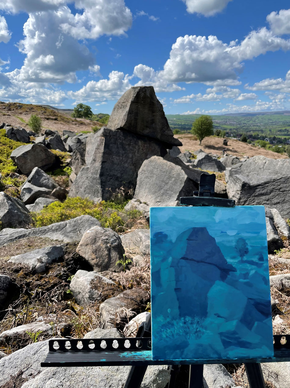 A painting on an easel before a rock on Ilkley Moor